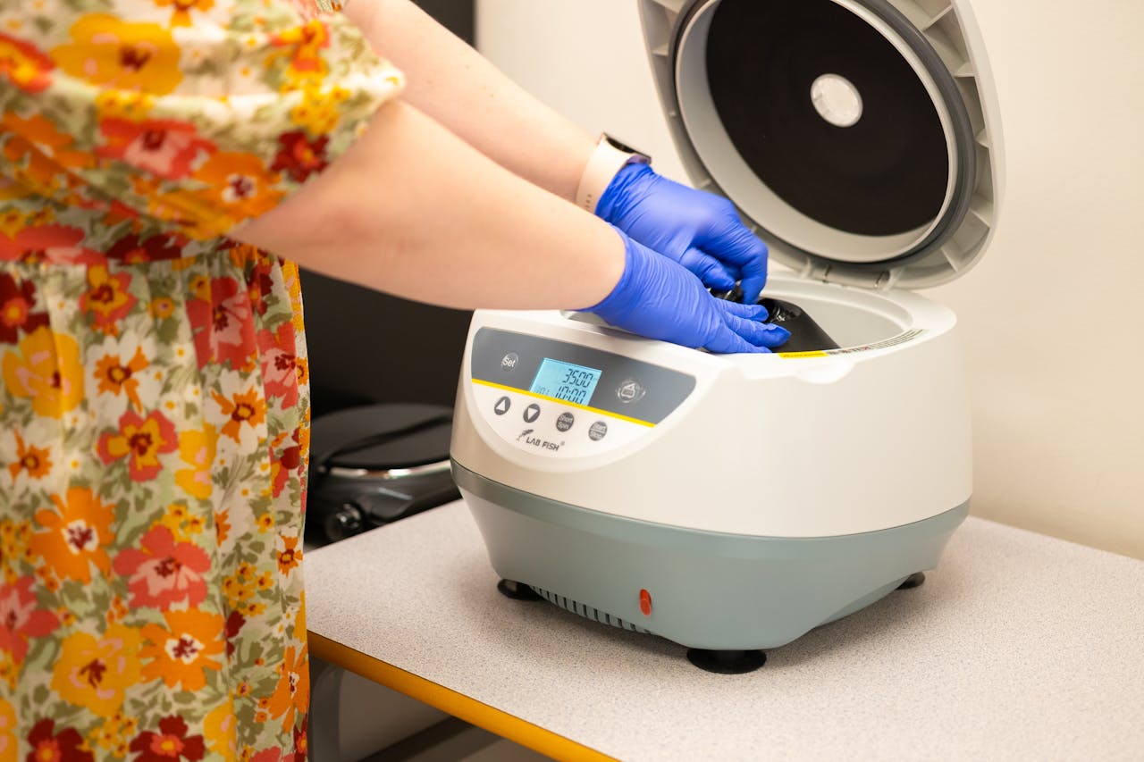 Scientist in gloves using a centrifuge for laboratory work indoors.